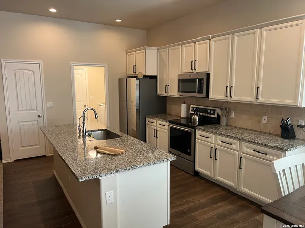 a kitchen with granite countertop white cabinets and stainless steel appliances