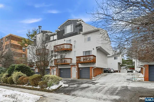 a view of a white house with a large tree in front of it