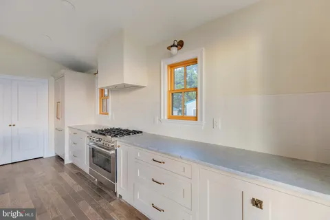 a view of an empty room with wooden floor and fan
