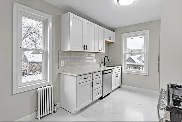 a kitchen with granite countertop white cabinets and window
