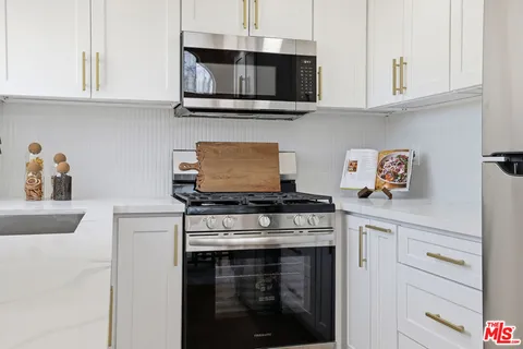 a kitchen with stainless steel appliances granite countertop white cabinets a stove a sink and dishwasher