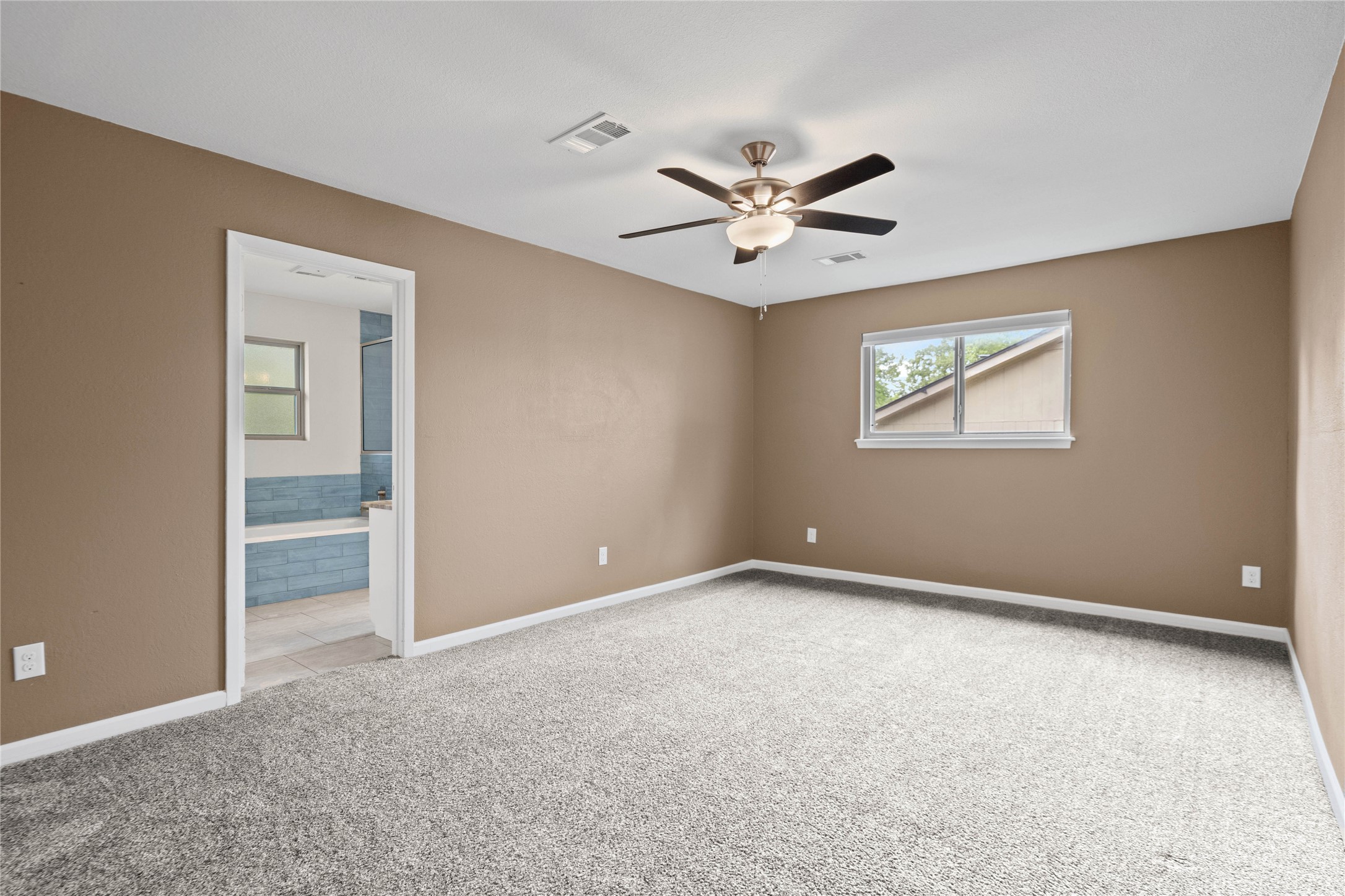 810 Stillhouse Spring Round Rock, TX 78681 - Photo 13 of 18 A spacious bedroom with plush carpeting features a ceiling fan and an adjacent full bathroom.