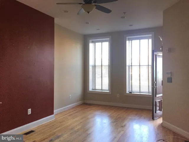 an empty room with windows and fan