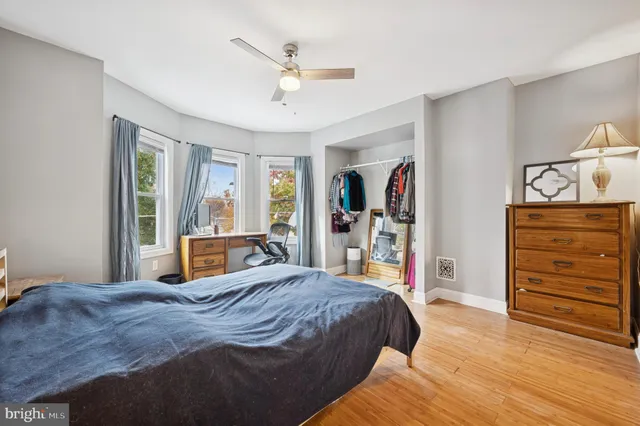 a bedroom with a bed a dresser and painting on the wall