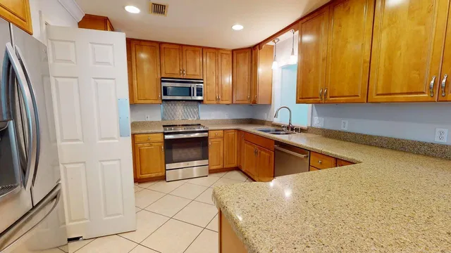 a kitchen with stainless steel appliances granite countertop a stove a sink and a microwave