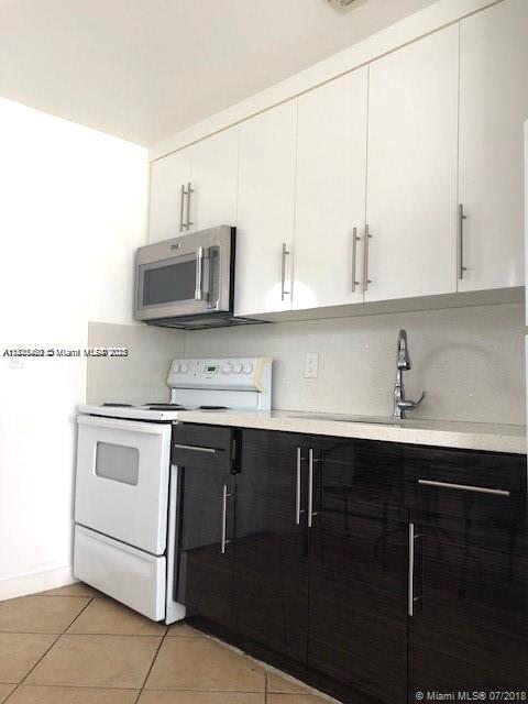 904 Southwest 7th Terrace, Unit 1 Hallandale Beach, FL 33009 - Photo 3 of 11 a kitchen with a sink cabinets and stainless steel appliances