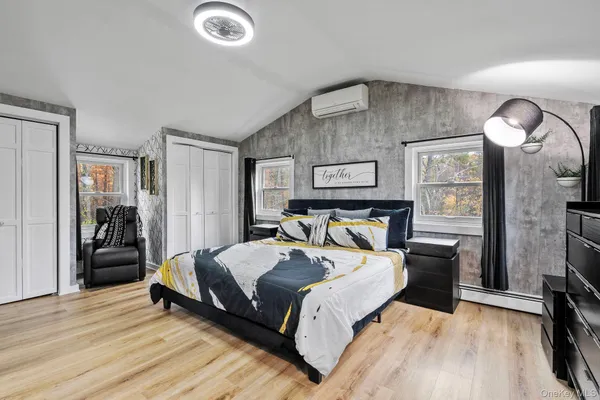 a spacious bedroom with a bed and wooden floor