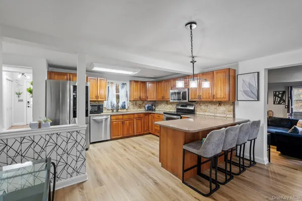 a kitchen with stainless steel appliances granite countertop a stove a sink dishwasher a dining table and chairs with wooden floor