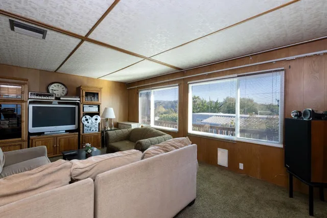 a living room with furniture a flat screen tv and a floor to ceiling window