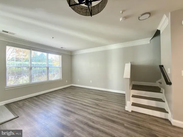 a view of an empty room with wooden floor and window