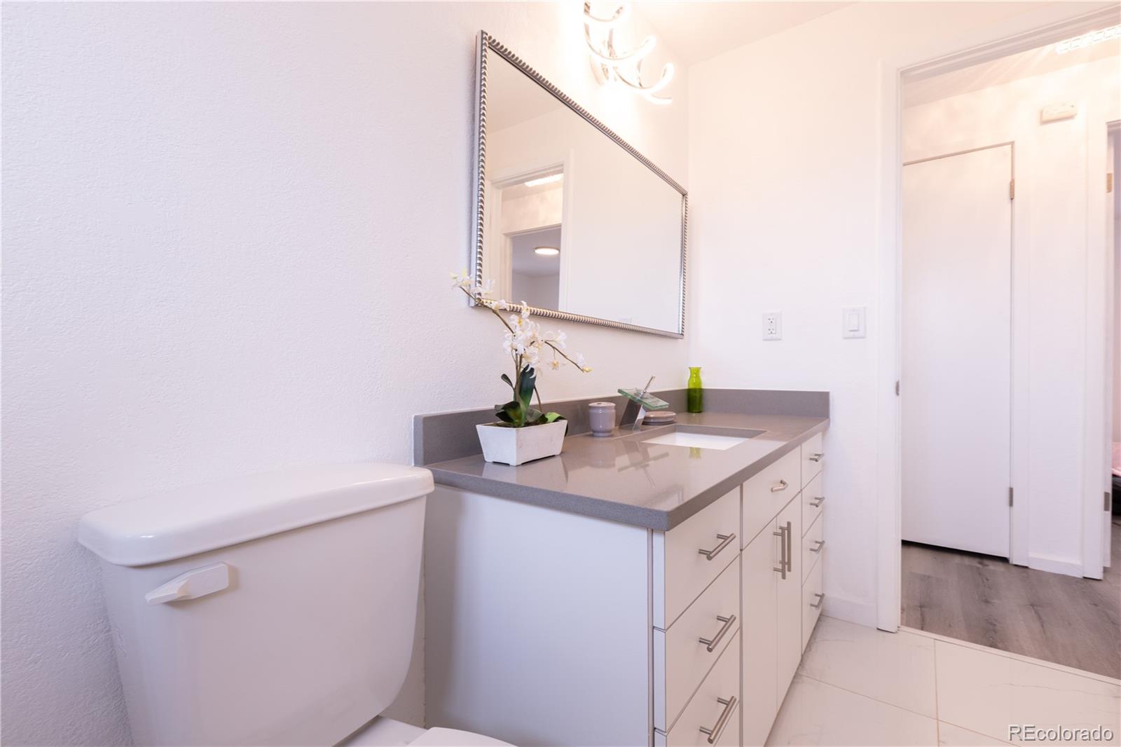 8243 Adams Way Denver, CO 80221 - Photo 11 of 27 a bathroom with a sink toilet and mirror