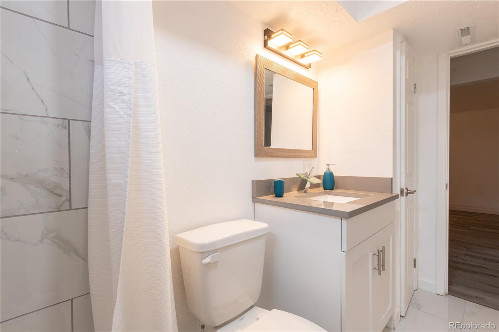 8243 Adams Way Denver, CO 80221 - Photo 21 of 27 a bathroom with a granite countertop sink a toilet and a mirror