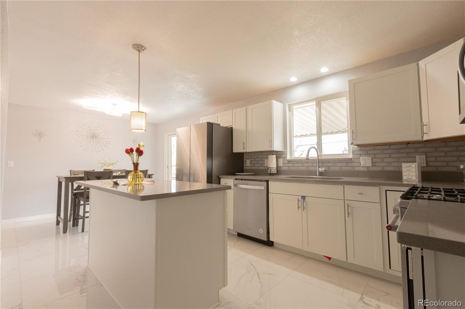 8243 Adams Way Denver, CO 80221 - Photo 5 of 27 a kitchen with stainless steel appliances granite countertop a sink a stove a refrigerator a center island and cabinets