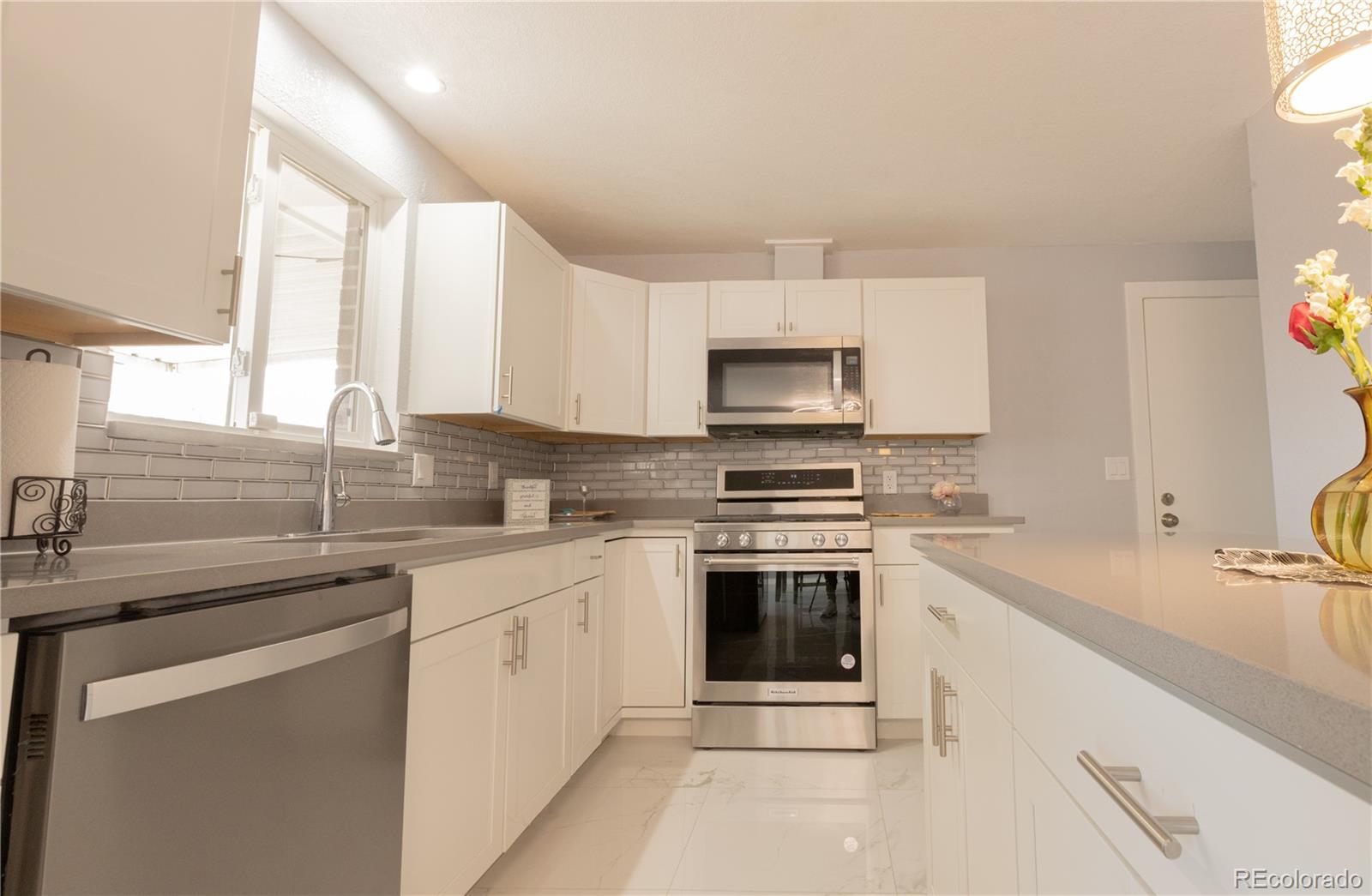 8243 Adams Way Denver, CO 80221 - Photo 6 of 27 a kitchen with a sink stove top oven and microwave