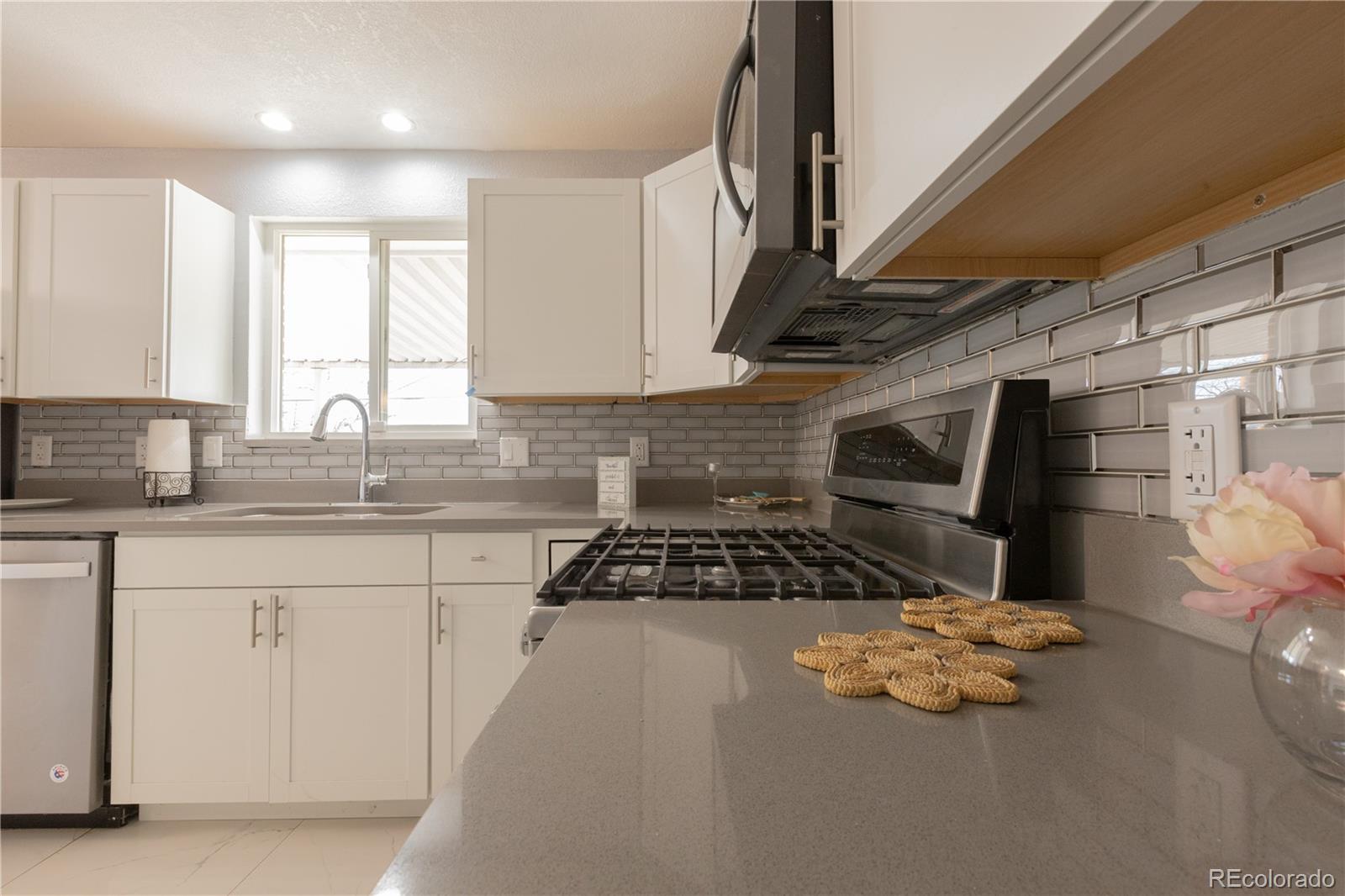 8243 Adams Way Denver, CO 80221 - Photo 7 of 27 a kitchen with granite countertop a stove sink and cabinets