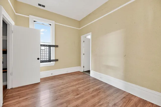 an empty room with wooden floor and windows