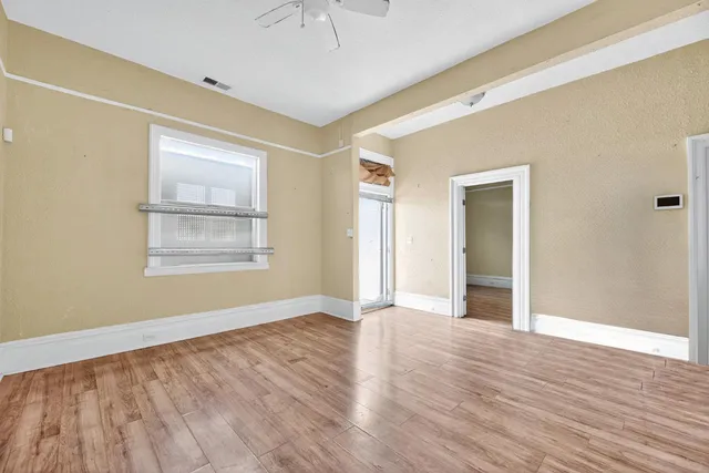 a view of an empty room with wooden floor and a window