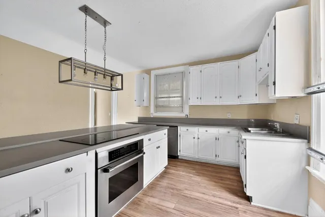 a kitchen with granite countertop a sink a stove and cabinets