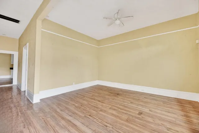 a view of a room with wooden floor and a ceiling fan