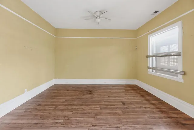 a view of an empty room with wooden floor and a window