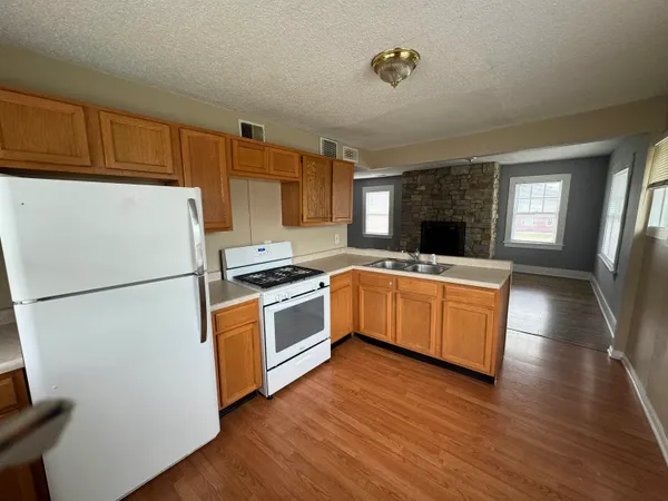 a kitchen with granite countertop a refrigerator a sink dishwasher stove and oven with wooden floor
