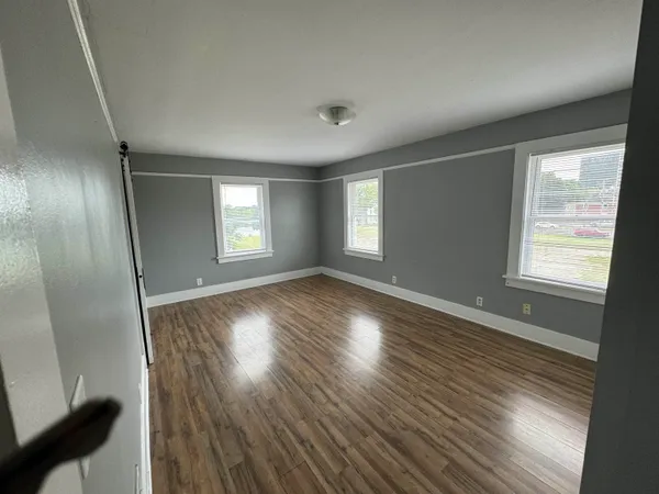 an empty room with wooden floor and windows