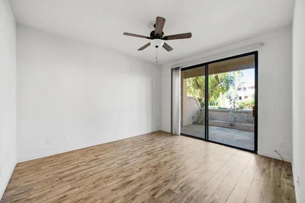 a view of empty room with wooden floor and fan