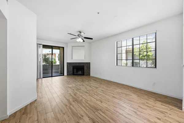 an empty room with wooden floor fireplace and windows