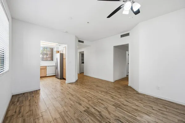 a view of an empty room with wooden floor and a window