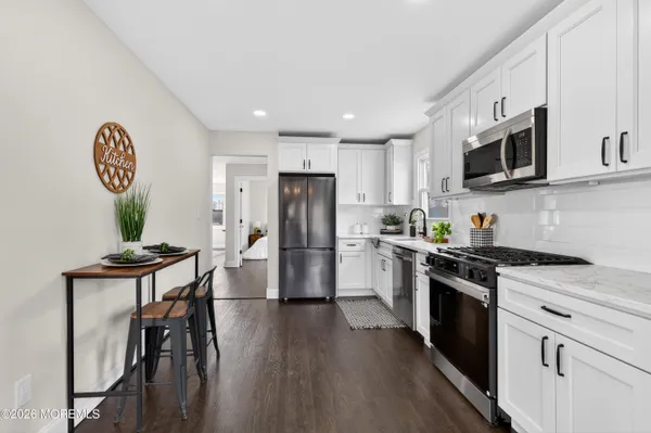 a kitchen with a refrigerator a stove top oven a sink dishwasher and white cabinets with wooden floor