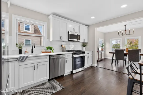 a kitchen with a stove top oven a sink dishwasher a dining table and chairs with wooden floor