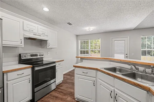 a kitchen with granite countertop a sink stainless steel appliances and window