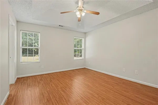 a view of empty room with wooden floor and fan