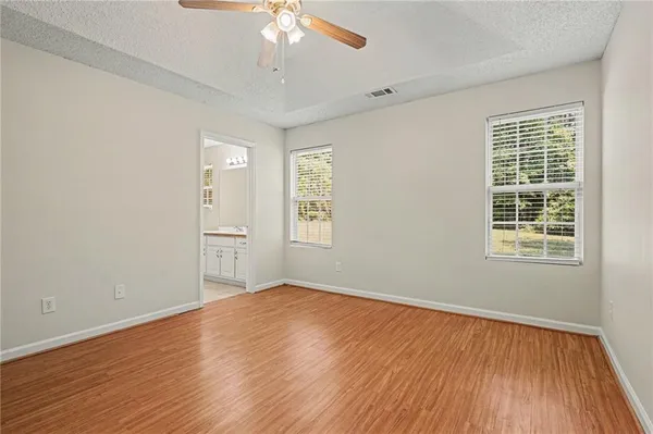 an empty room with wooden floor chandelier fan and windows