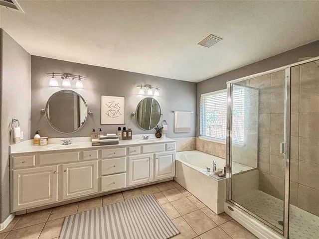 a bathroom with a double vanity sink mirror and bathtub