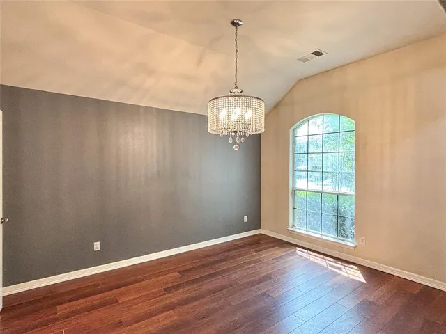 a view of a room with wooden floor chandelier and windows