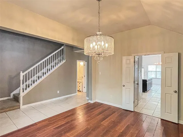a view of a hallway with wooden floor and chandelier