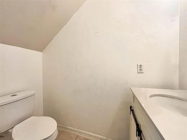 a white toilet sitting next to a white sink and vanity