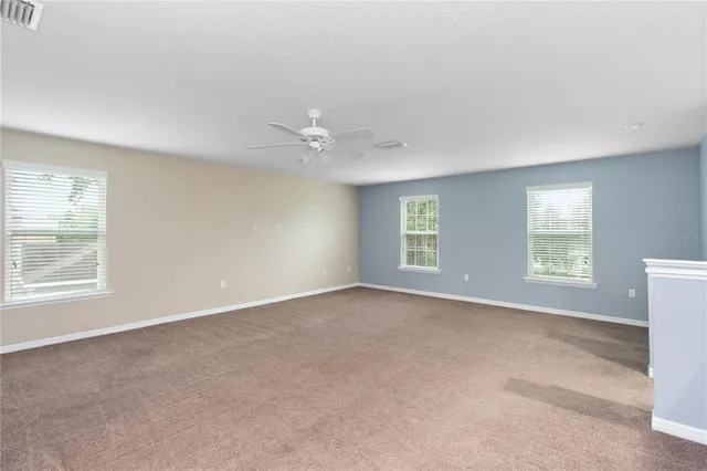an empty room with a window and a ceiling fan
