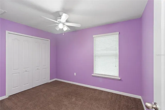 an empty room with a window and a ceiling fan