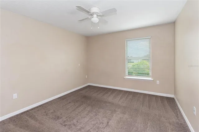an empty room with a ceiling fan and a window