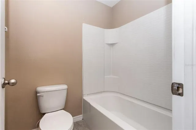 a view of a hallway with wooden floor and a bathroom