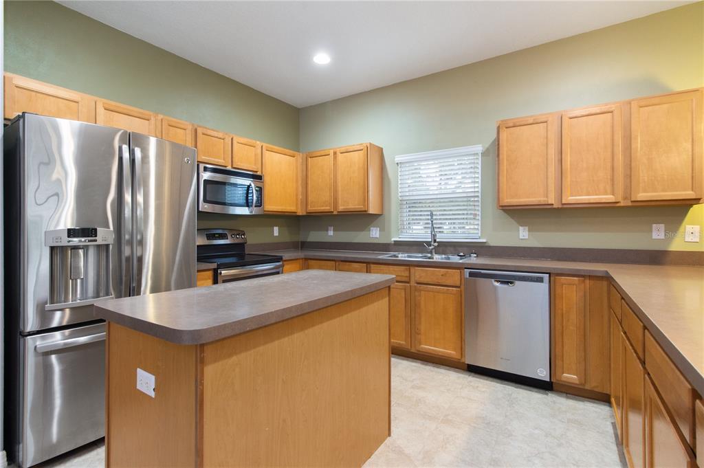 13222 Weatherstone Drive Spring Hill, FL 34609 - Photo 34 of 46 a kitchen with stainless steel appliances granite countertop a refrigerator a sink a stove a washer dryer and a refrigerator