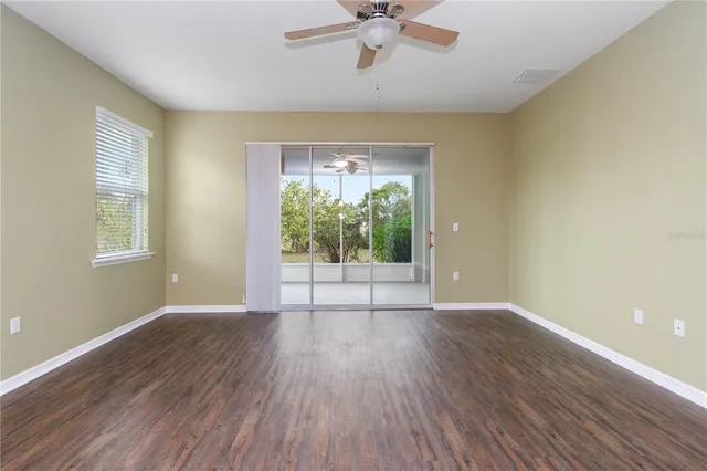 an empty room with wooden floor and kitchen view