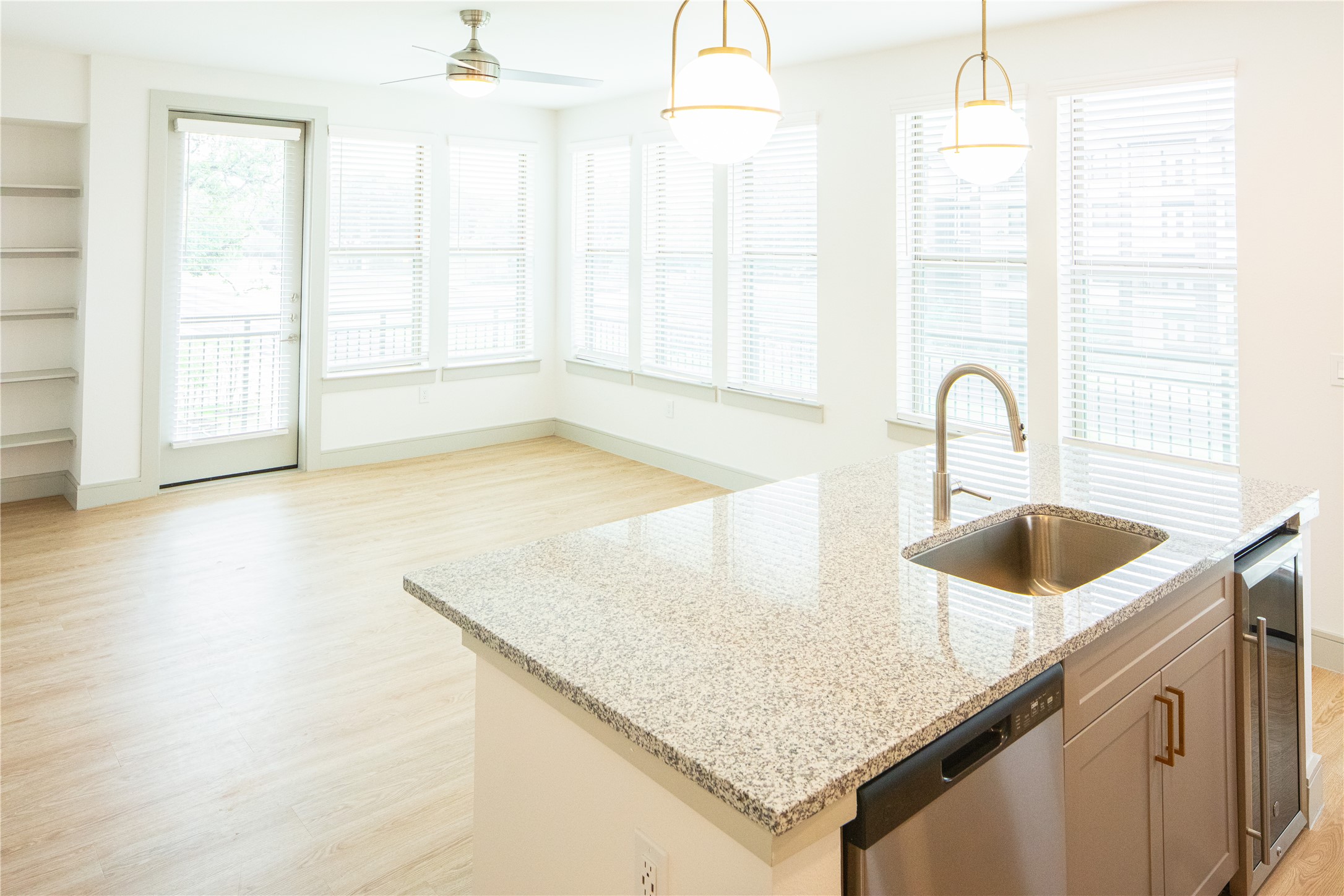 3100 Scofield Ridge Parkway, Unit 1125 Austin, TX 78727 - Photo 15 of 21 Kitchen with light wood finished floors, a center island with sink, light stone countertops, stainless steel dishwasher, and a sink