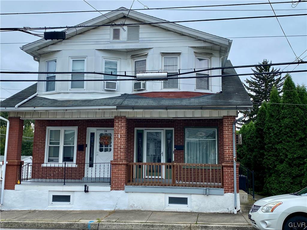 a view of a white house with large windows and a small yard