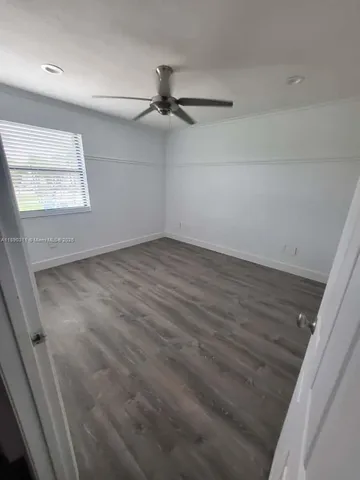 en empty room with wooden floor fan and windows