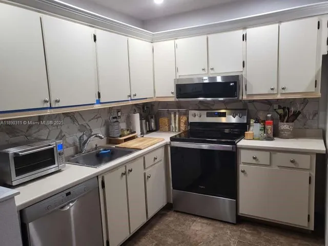 a kitchen with stainless steel appliances a stove a sink and cabinets