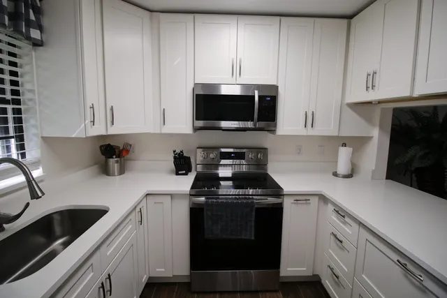 a kitchen with white cabinets and black appliances