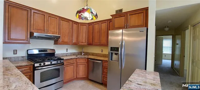 a kitchen with stainless steel appliances granite countertop a refrigerator a stove and a sink with wooden floor